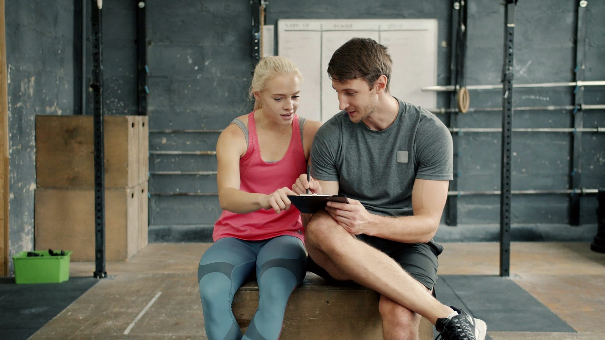 Trenér a klientka spolu procházejí tréninkový plán na tabletu